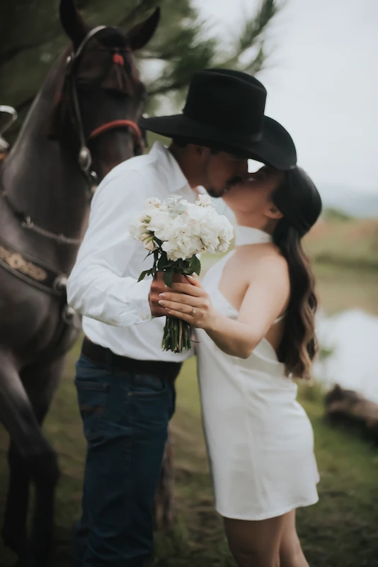 Imagen de la pareja besándose con un ramo de rosas blancas